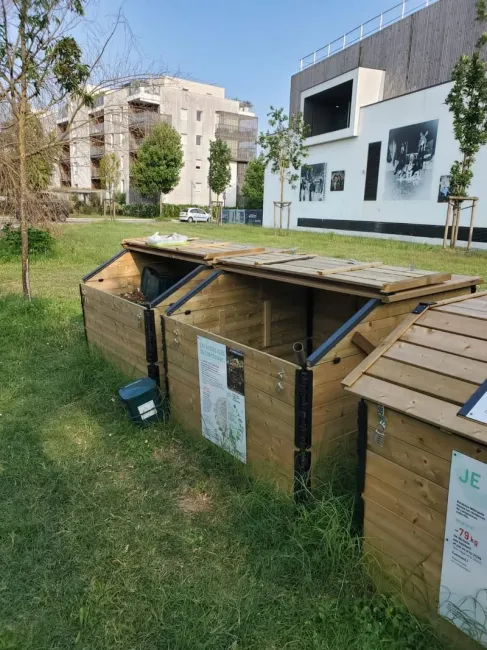 3 bac en bois: 1 bac de brun, 1 bac de compost et un bac de maturation, situés sur une prairie herbeuse au milieu d'un quartir résidentiel