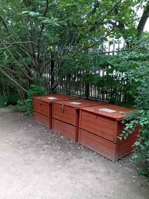 Trois bacs en bois, rouges, au fond du jardin sur le chemin.