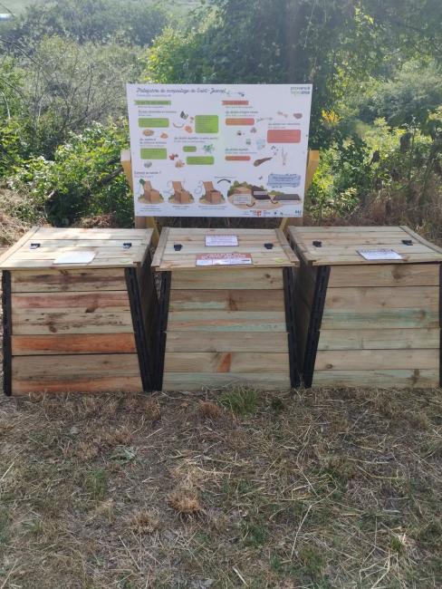 Emplacement du site à proximité des colonnes de tri. Bacs bois avec panneau explicatif.
